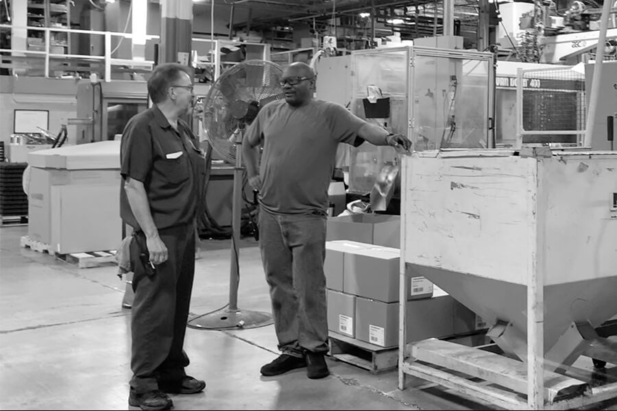 two-male-workers-talking-at-injection-molding-machine